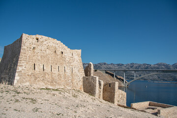 PAG ISLAND, CROATIA, 10.10.2020. Ruins of Fortica fortress and Pag bridge in distance
