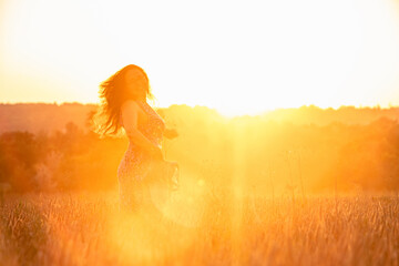 beautiful mature woman in sundress at wheat field on sunset