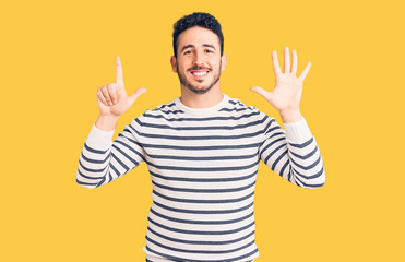 Naklejka premium Young hispanic man wearing casual clothes showing and pointing up with fingers number seven while smiling confident and happy.