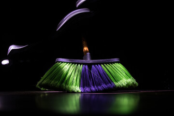 close-up brush the floor on a dark background with light and fog. Broom in dark. Cleaning concept.