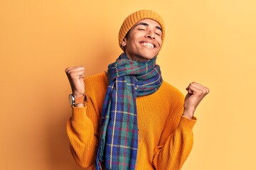 Young african amercian man wearing casual winter clothes very happy and excited doing winner gesture with arms raised, smiling and screaming for success. celebration concept.