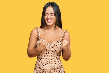 Young beautiful hispanic girl wearing sexy party dress excited for success with arms raised and eyes closed celebrating victory smiling. winner concept.