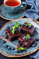 Chocolate  brownie cakes with cup of tea and blueberry on dark background