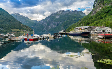 Fototapeta na wymiar Urlaub in Süd-Norwegen: der epische Geiranger Fjord - der kleine Hafen vom Ort Geiranger mit bunten Booten und Fähre