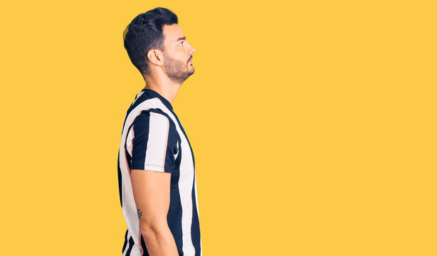 Young handsome hispanic man wearing striped tshirt looking to side, relax profile pose with natural face with confident smile.