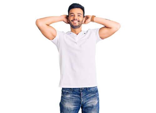 Young handsome hispanic man wearing casual clothes relaxing and stretching, arms and hands behind head and neck smiling happy