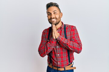 Handsome man with beard wearing hipster elegant look praying with hands together asking for...