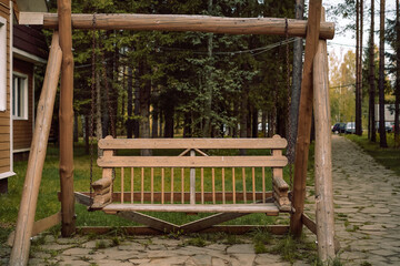 solid wooden garden swings next to wooden house in the countryside