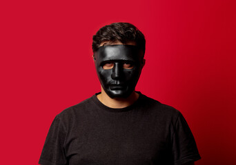White man in black mask on red background