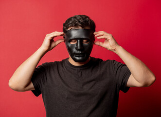 White man in black mask on red background