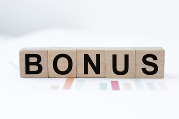 Word bonus on wooden cubes on the table. Concept bonus is any financial compensation.