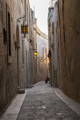Fototapeta na wymiar woman sitting alone in a narrow street of Mdina, Malta