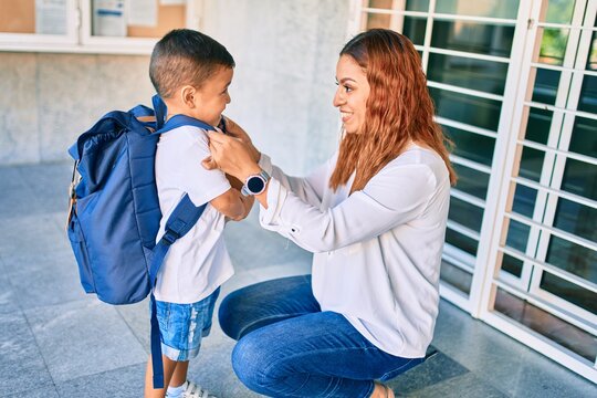 Adorable latin student boy and mom at school. Mother preparing kid putting up backpack.