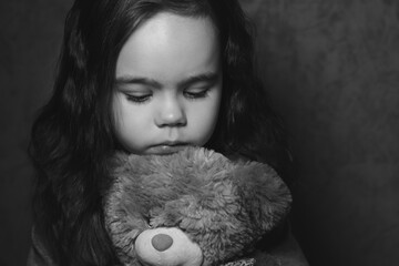 Sad girl with a toy looked down black and white photo
