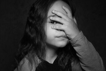 Girl looks through her fingers black and white photo