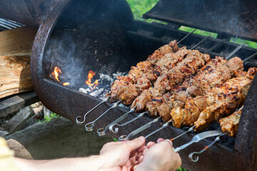 Meat are fried on the barbecue, man is grilling  meat over the coals, picnic in the nature, shashlik roasting on the barbecue, nature background