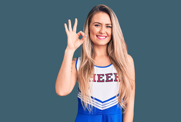 Young beautiful blonde woman wearing cheerleader uniform smiling positive doing ok sign with hand and fingers. successful expression.