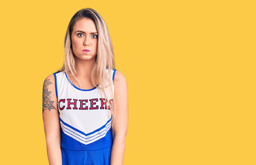 Young beautiful blonde woman wearing cheerleader uniform puffing cheeks with funny face. mouth...