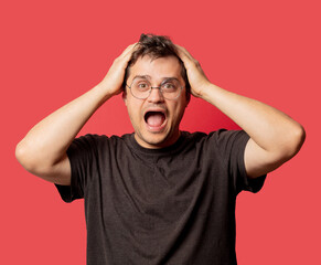 surprised man in glasses and shirt on red background