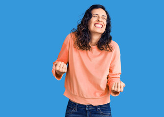 Young beautiful hispanic woman wearing casual clothes very happy and excited doing winner gesture with arms raised, smiling and screaming for success. celebration concept.