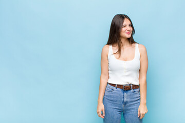 youn pretty woman looking happy and friendly, smiling and winking an eye at you with a positive...