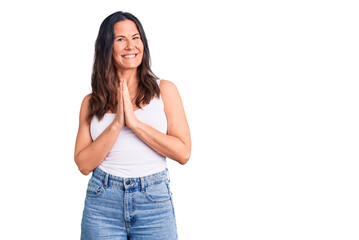 Obraz premium Young beautiful brunette woman wearing casual sleeveless t-shirt praying with hands together asking for forgiveness smiling confident.