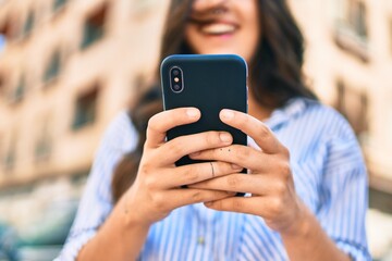 Young hispanic businesswoman smiling happy using smartphone at the city.