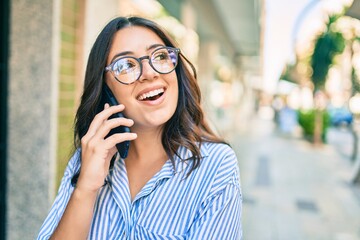 Young hispanic businesswoman smiling happy talking on the smartphone at the city.