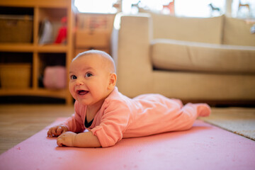 Smiling Baby Girl Lying Down on a Pink Rug