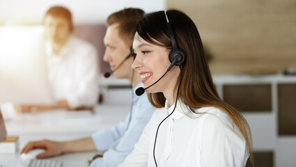 Asian woman working at customer service office. Business concept. Group of diverse operators at work in sunny call center.