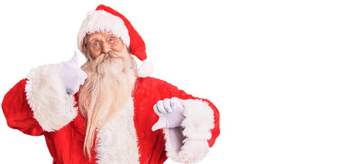 Old senior man with grey hair and long beard wearing traditional santa claus costume doing thumbs up and down, disagreement and agreement expression. crazy conflict