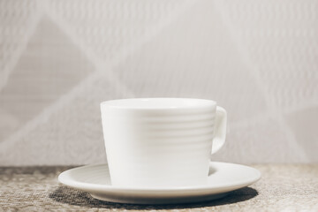 Empty cup on a wooden table top against a light wall, vintage design