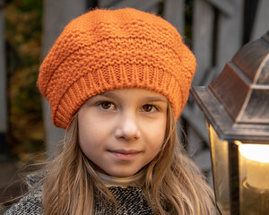Halloween autumn kids. Portrait magic girl in coat, hat with street lantern in park.