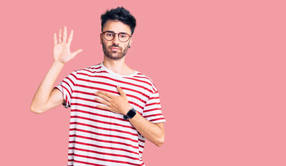 Fototapeta premium Young hispanic man wearing casual clothes swearing with hand on chest and open palm, making a loyalty promise oath