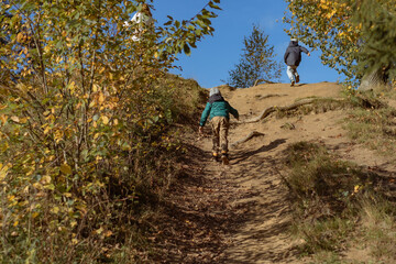 two boys climbing up the hill in autumn park