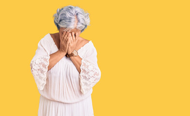 Senior woman with gray hair wearing bohemian style with sad expression covering face with hands while crying. depression concept.