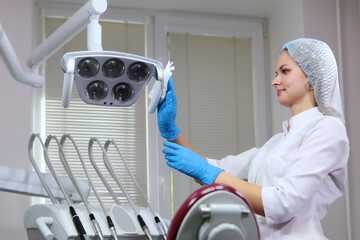 Doctor's assistant lapping lighting equipment.Disinfection of dental equipment before receiving...