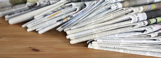 pile of newspapers on a wooden table