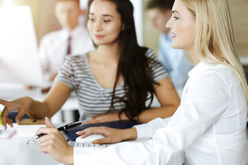 Group of business people discussing questions at meeting. Portrait of blond businesswoman in sunny office