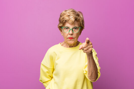 Old Pretty Woman Pointing At Camera With An Angry Aggressive Expression Looking Like A Furious, Crazy Boss