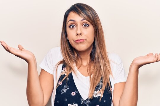 Young beautiful woman wearing casual floral dress clueless and confused with open arms, no idea and doubtful face.