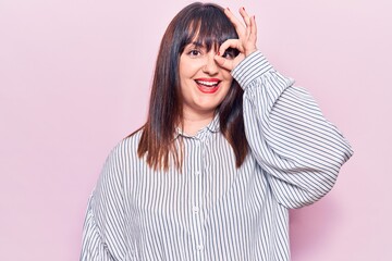 Young plus size woman wearing casual clothes doing ok gesture with hand smiling, eye looking through fingers with happy face.