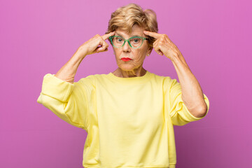 old pretty woman with a serious and concentrated look, brainstorming and thinking about a...