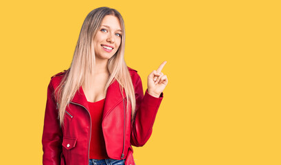 Young beautiful blonde woman wearing red leather jacket smiling happy pointing with hand and finger to the side