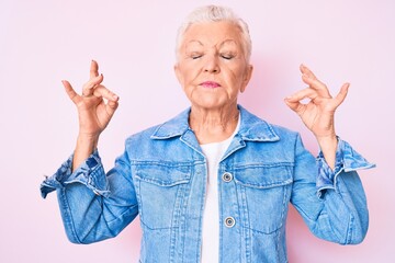 Senior beautiful woman with blue eyes and grey hair wearing casual denim jacket relax and smiling with eyes closed doing meditation gesture with fingers. yoga concept.