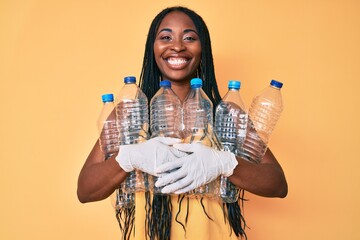 African american woman with braids holding recycling plastic bottles smiling with a happy and cool smile on face. showing teeth. - Powered by Adobe