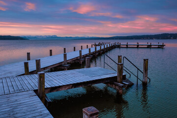 Fototapeta premium Sonnenaufgang am Starnberger See in Starnberg/Percha mit Bootshütten im verschneiten Winter