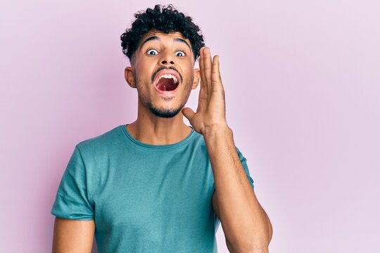 Young arab handsome man wearing casual clothes shouting and screaming loud to side with hand on mouth. communication concept.