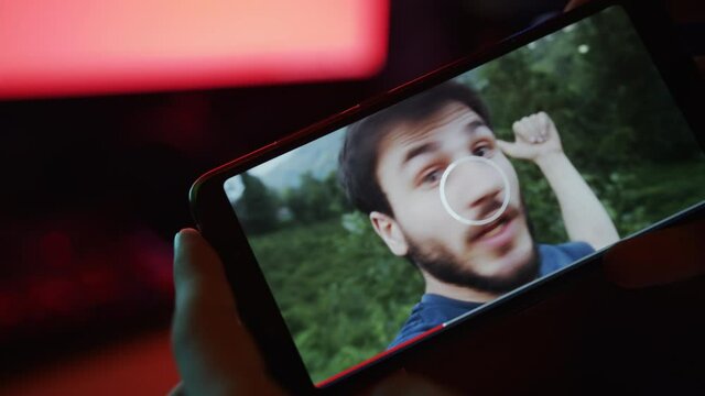 The man is watching a video with the phone in his hand and a vlogger or an influencer shooting video in a video player interface on the phone, video loading problems loading interface