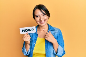 Beautiful young woman with short hair holding paper with how message smiling happy pointing with hand and finger